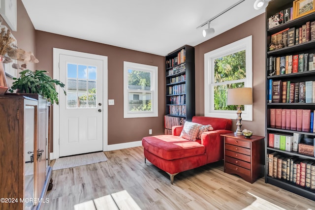 sitting room featuring track lighting, wood finished floors, and baseboards