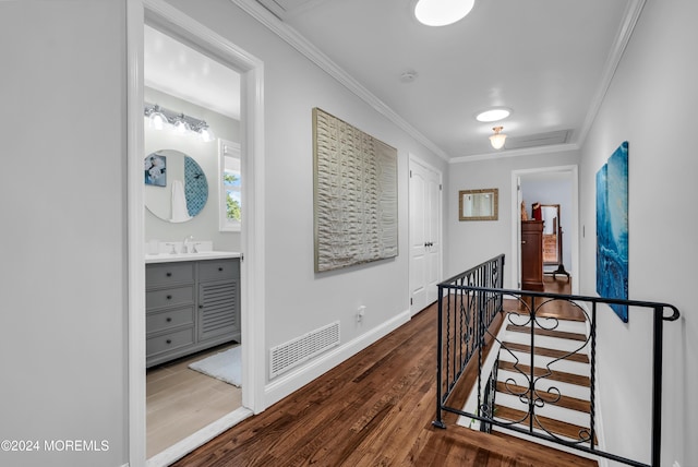 corridor featuring crown molding, wood finished floors, an upstairs landing, and visible vents