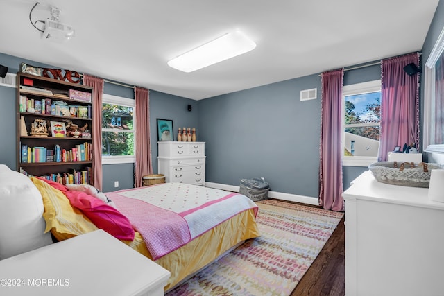 bedroom with visible vents, baseboards, and wood finished floors