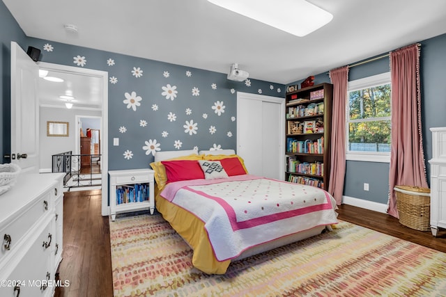 bedroom featuring a closet, wallpapered walls, baseboards, and hardwood / wood-style flooring