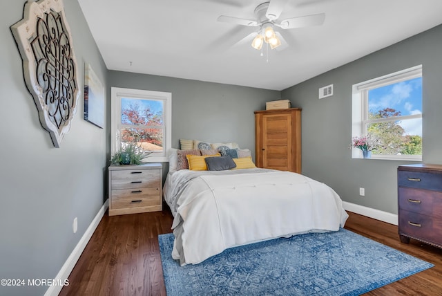 bedroom with dark wood-type flooring, visible vents, baseboards, and ceiling fan