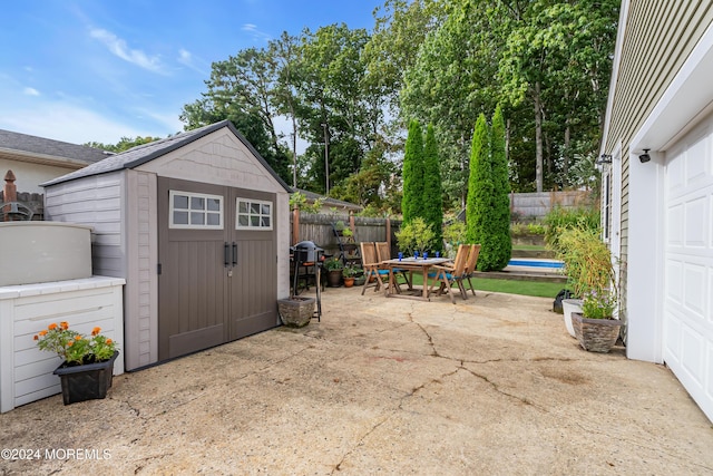 view of patio with an outbuilding, a storage shed, and fence