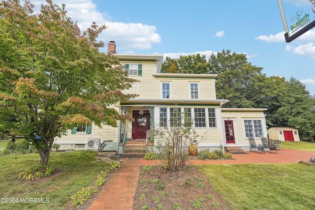 view of front of house with an outbuilding, entry steps, a patio, a storage unit, and a front yard