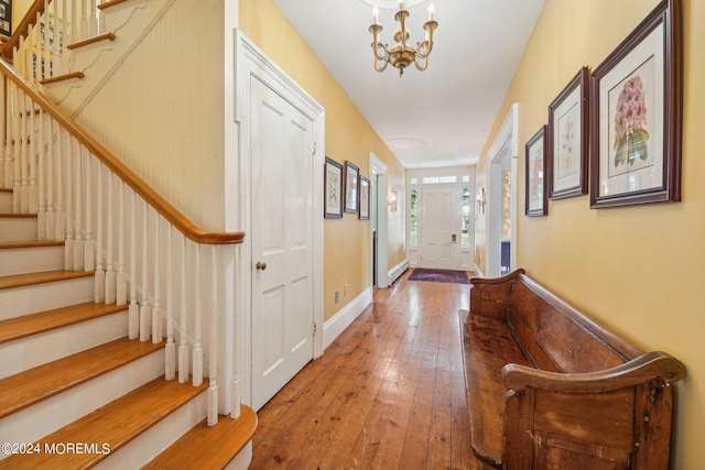 corridor featuring a chandelier, hardwood / wood-style floors, and stairs