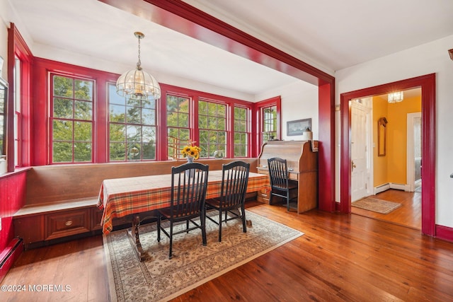 dining area with breakfast area, a chandelier, baseboard heating, wood-type flooring, and baseboards