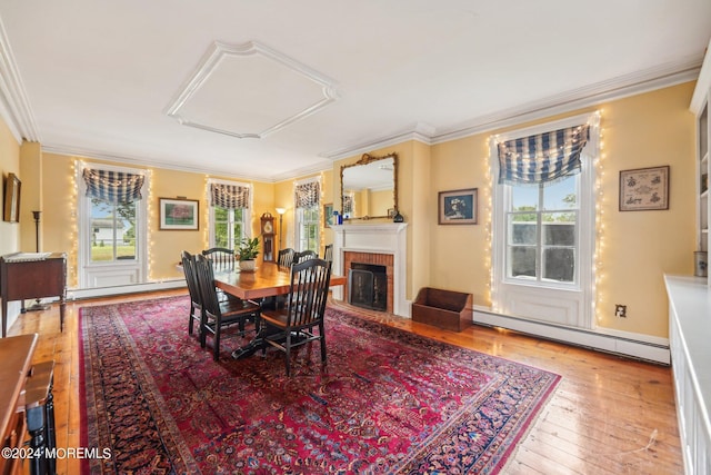 dining area featuring crown molding, wood-type flooring, a brick fireplace, and baseboard heating