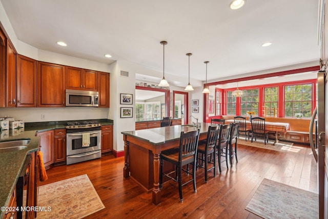 kitchen with a kitchen bar, visible vents, recessed lighting, appliances with stainless steel finishes, and dark wood-style flooring