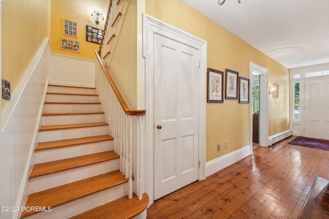 entrance foyer with a baseboard radiator, hardwood / wood-style floors, and stairs
