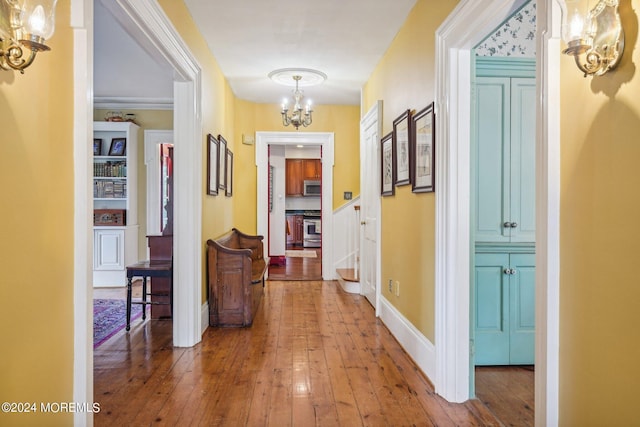 hallway with a chandelier, hardwood / wood-style flooring, and baseboards