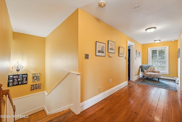 hallway with an upstairs landing, hardwood / wood-style flooring, baseboards, and a wainscoted wall