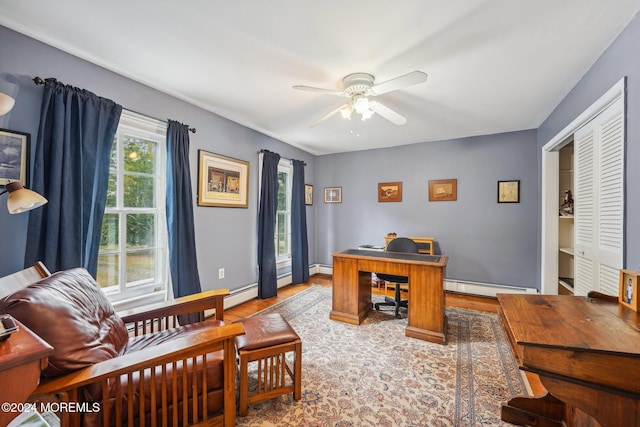 office area featuring baseboard heating, wood finished floors, and a ceiling fan