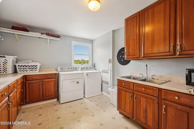 clothes washing area with independent washer and dryer, radiator heating unit, a sink, and cabinet space