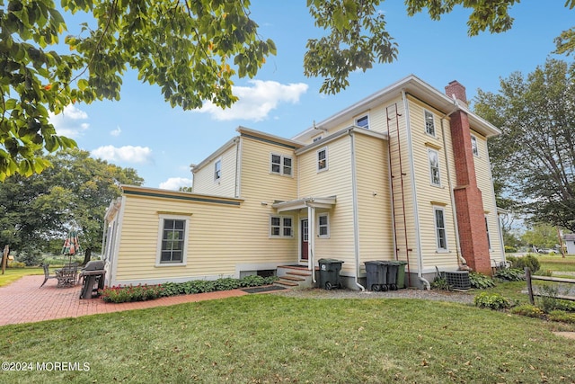 rear view of property featuring central air condition unit, a yard, a patio, fence, and a chimney