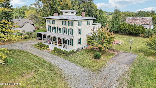 view of front of property featuring a porch, a chimney, gravel driveway, and a front lawn