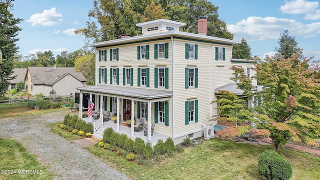 exterior space with a chimney, driveway, a front yard, a porch, and fence
