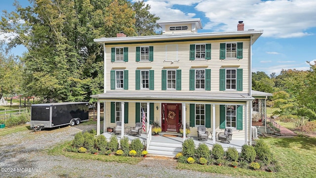 italianate house with a porch, a chimney, and driveway