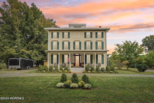 italianate-style house featuring covered porch and a lawn