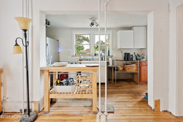 kitchen featuring decorative backsplash, white cabinets, and light wood-type flooring