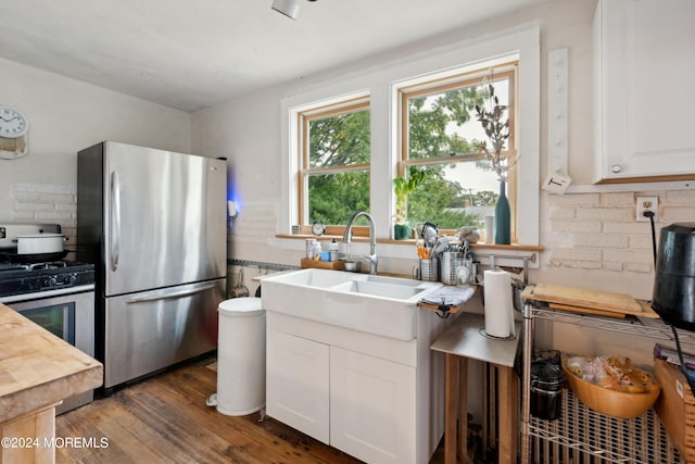 kitchen with stainless steel fridge, sink, gas range gas stove, dark wood-type flooring, and white cabinetry