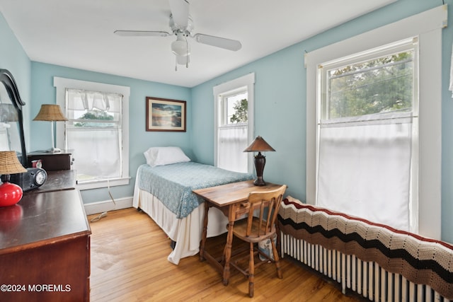 bedroom with ceiling fan, light hardwood / wood-style floors, and radiator heating unit