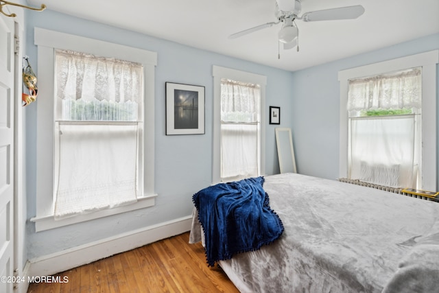 bedroom featuring multiple windows, hardwood / wood-style floors, and ceiling fan