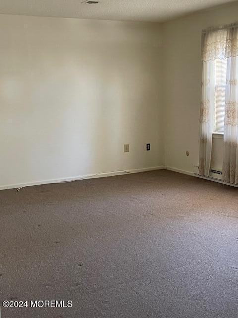 carpeted empty room with a textured ceiling