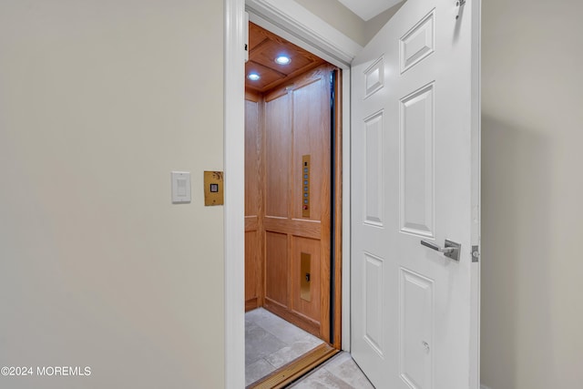 corridor with light tile patterned floors and elevator