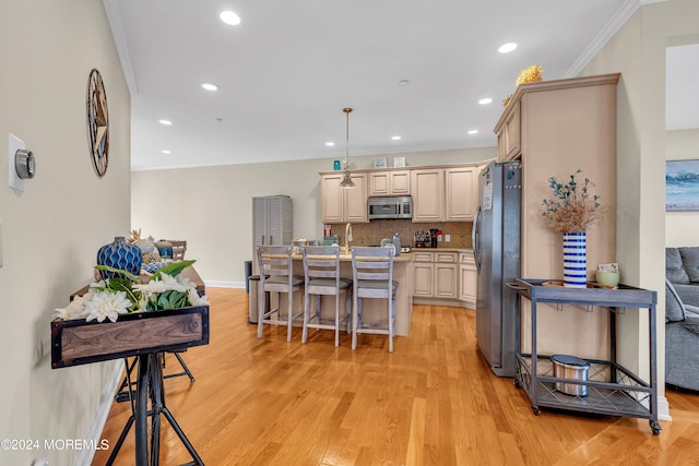 kitchen featuring decorative light fixtures, backsplash, stainless steel appliances, crown molding, and light hardwood / wood-style floors