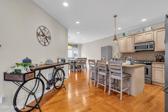 kitchen featuring light stone counters, a center island with sink, appliances with stainless steel finishes, and light wood-type flooring