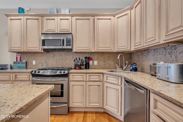 kitchen with light hardwood / wood-style flooring, stainless steel appliances, tasteful backsplash, and sink