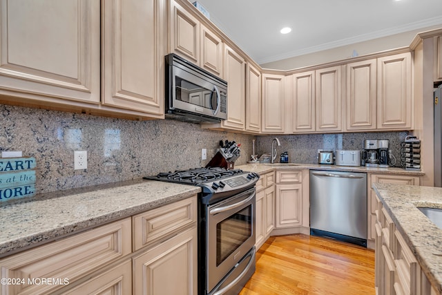 kitchen featuring light stone counters, stainless steel appliances, crown molding, and tasteful backsplash