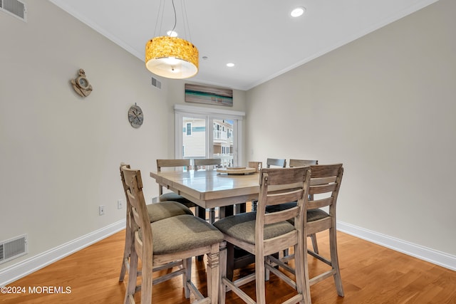 dining area with light hardwood / wood-style flooring and ornamental molding