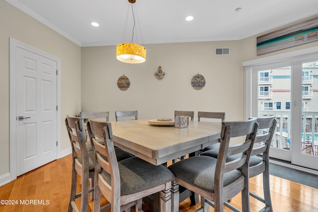 dining space with light hardwood / wood-style flooring and ornamental molding