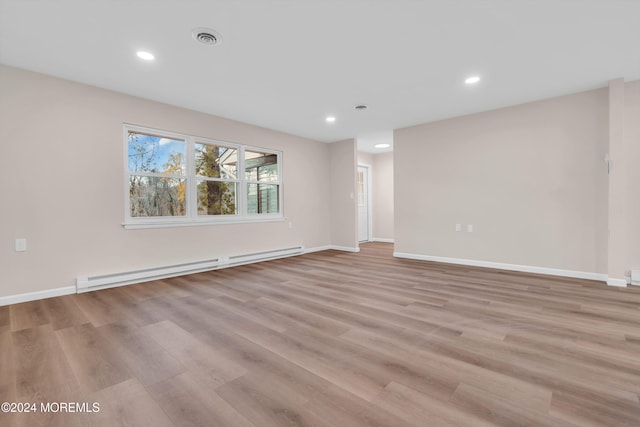 unfurnished room featuring baseboard heating and light wood-type flooring