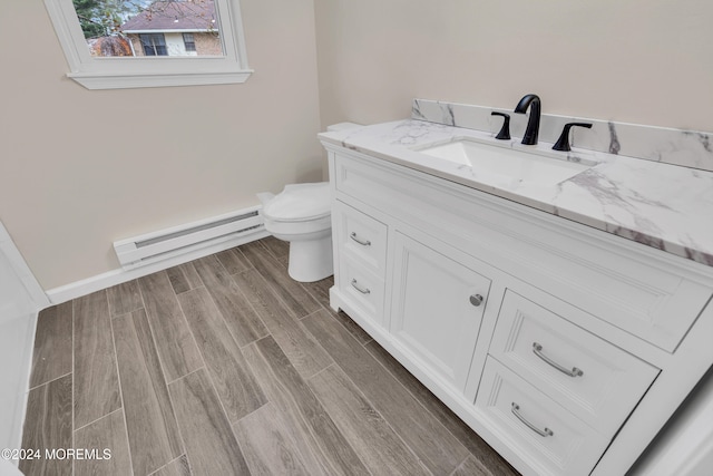 bathroom with toilet, vanity, a baseboard radiator, and hardwood / wood-style flooring