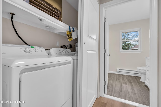 laundry area featuring separate washer and dryer, a baseboard radiator, and light wood-type flooring