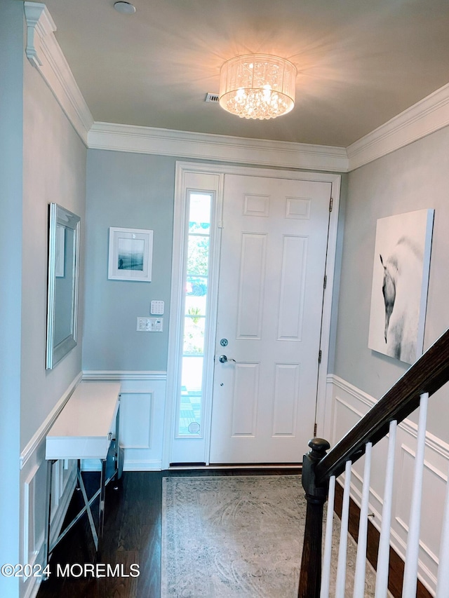 entryway with ornamental molding, a notable chandelier, and dark hardwood / wood-style floors