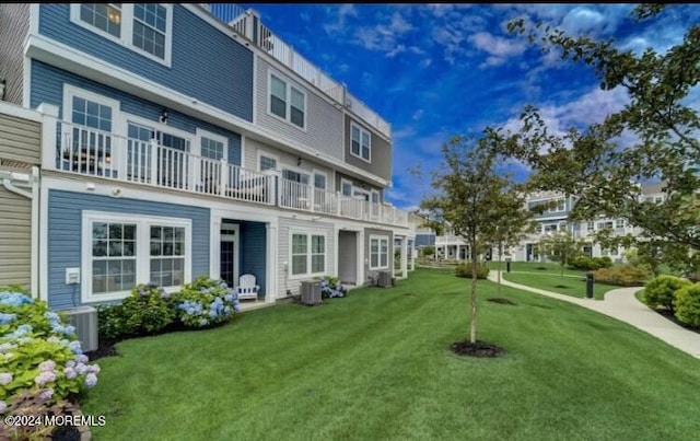 rear view of house featuring a lawn and a balcony