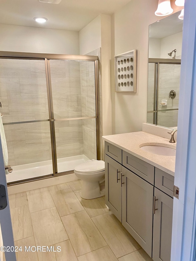 bathroom with vanity, a shower with shower door, and toilet