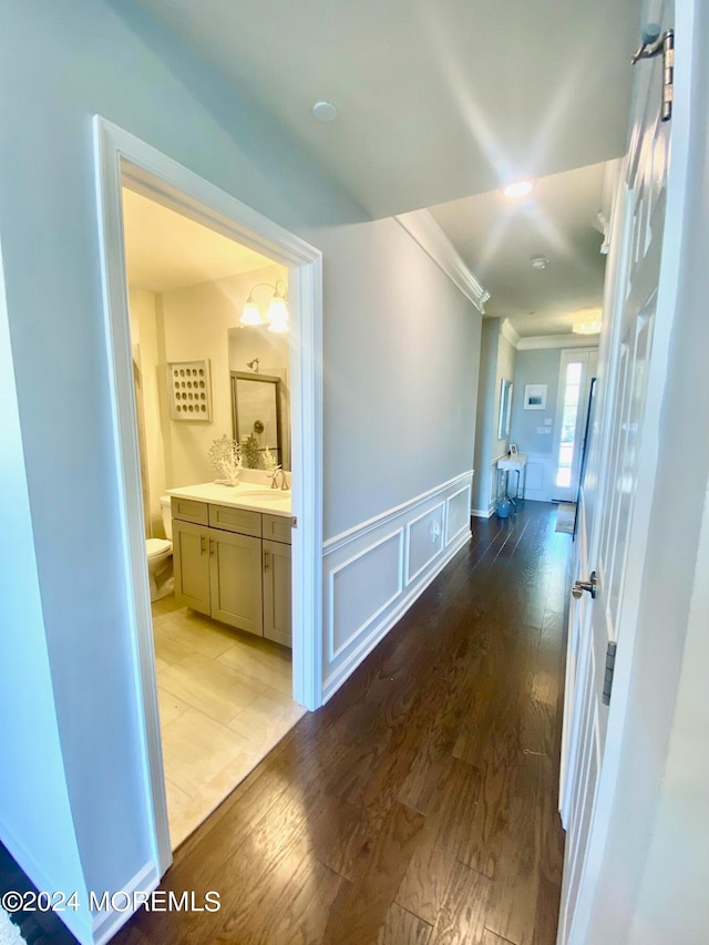 hall with light wood-type flooring, crown molding, and sink