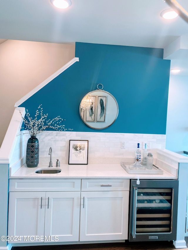 bar with wine cooler, white cabinetry, tasteful backsplash, and sink