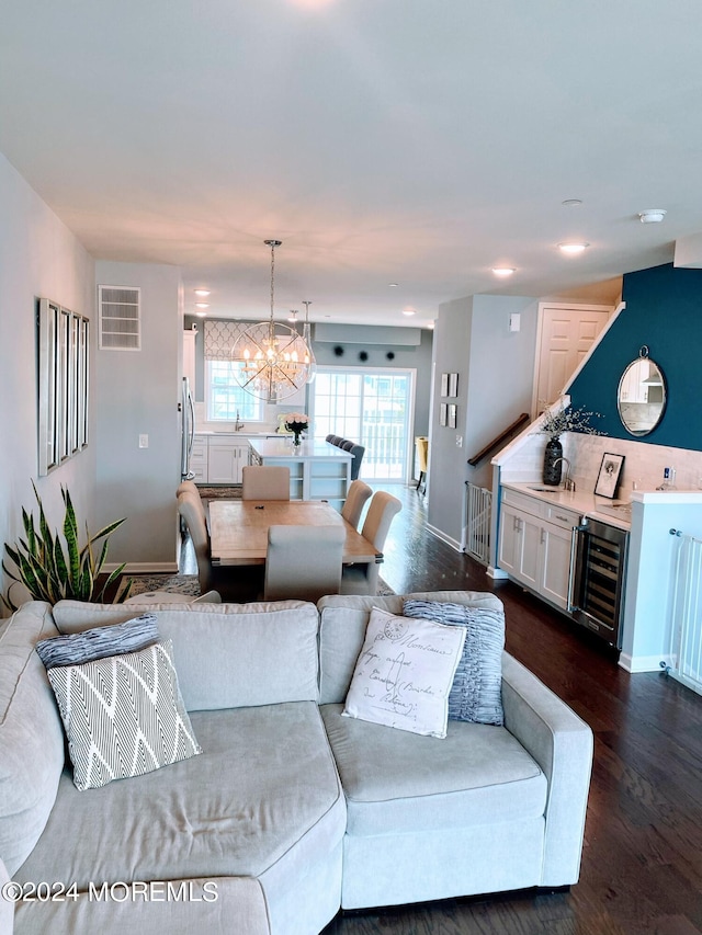 living room with an inviting chandelier, wine cooler, and dark hardwood / wood-style floors