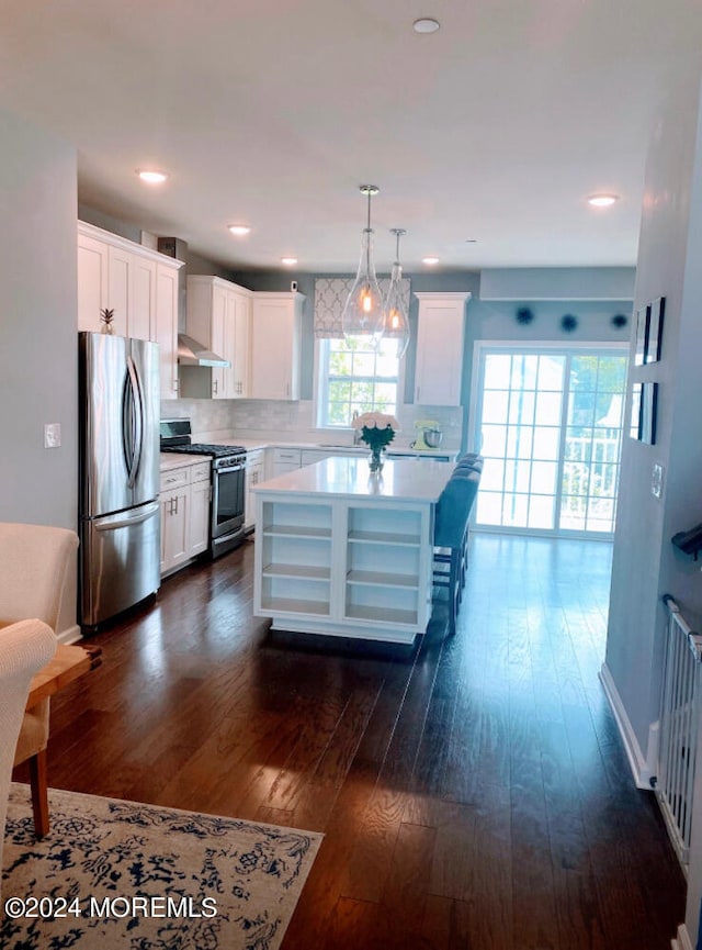 kitchen with hanging light fixtures, white cabinetry, appliances with stainless steel finishes, dark hardwood / wood-style floors, and a center island