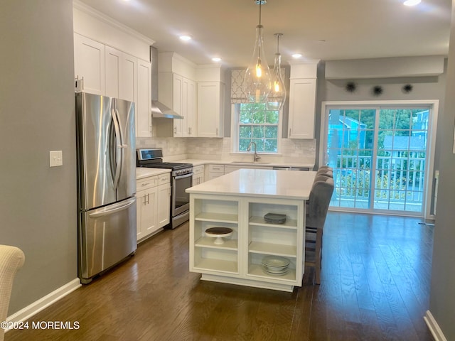 kitchen featuring appliances with stainless steel finishes, white cabinetry, a center island, dark hardwood / wood-style floors, and wall chimney range hood