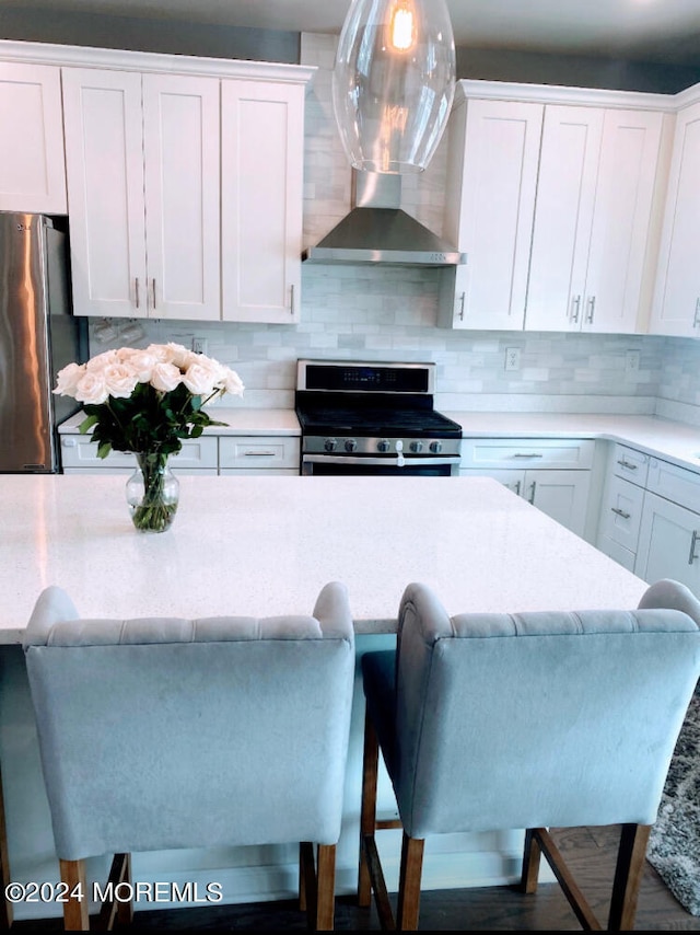 kitchen with hanging light fixtures, tasteful backsplash, white cabinetry, appliances with stainless steel finishes, and a breakfast bar