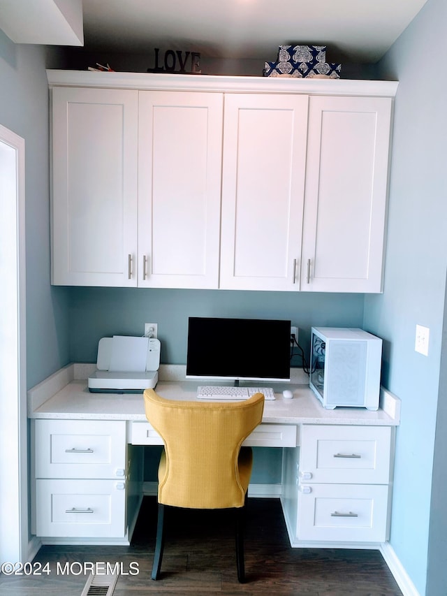 home office with built in desk and dark hardwood / wood-style flooring