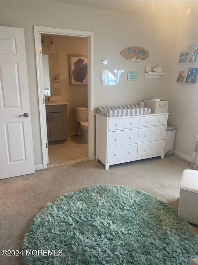 carpeted bedroom with sink and ensuite bathroom