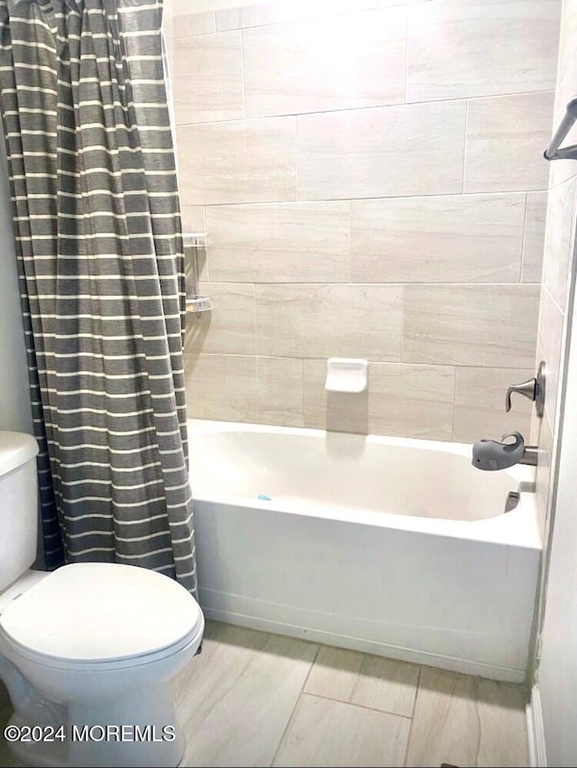 bathroom with shower / tub combo with curtain and toilet