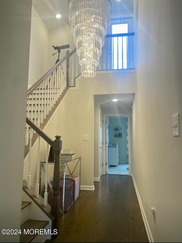 stairway with hardwood / wood-style floors and a notable chandelier