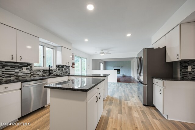 kitchen with appliances with stainless steel finishes, light hardwood / wood-style floors, a center island, and white cabinets